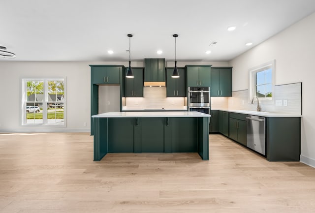 kitchen with a healthy amount of sunlight, stainless steel appliances, decorative light fixtures, and light wood-type flooring