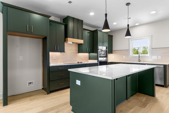 kitchen with a center island, stainless steel appliances, light hardwood / wood-style flooring, decorative light fixtures, and green cabinetry