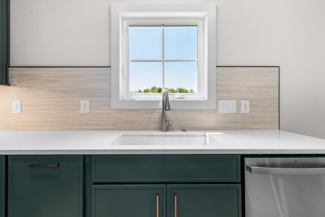 kitchen featuring tasteful backsplash, stainless steel dishwasher, green cabinets, and sink