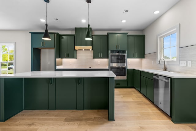 kitchen featuring pendant lighting, stainless steel appliances, green cabinets, and sink