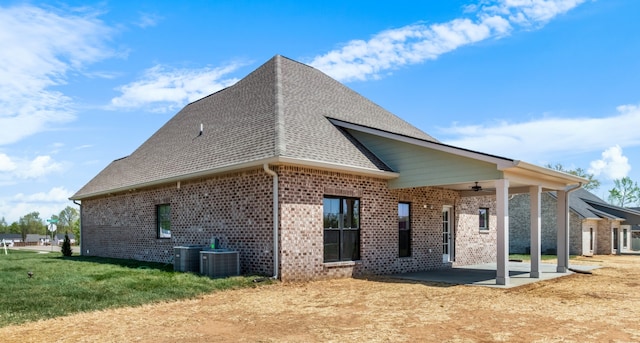 rear view of property featuring a lawn, ceiling fan, cooling unit, and a patio