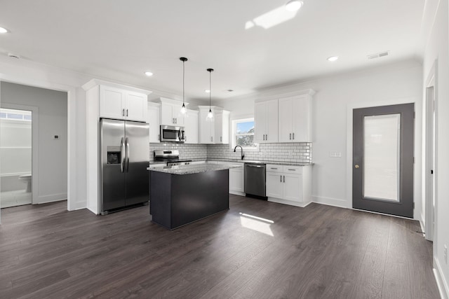 kitchen featuring appliances with stainless steel finishes, a kitchen island, dark wood-type flooring, and decorative light fixtures