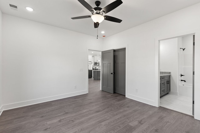 unfurnished bedroom with a closet, ceiling fan, dark hardwood / wood-style floors, and ensuite bathroom