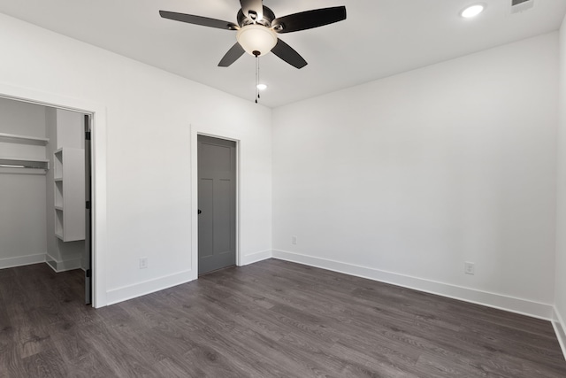 unfurnished bedroom with ceiling fan, a closet, dark hardwood / wood-style flooring, and a walk in closet