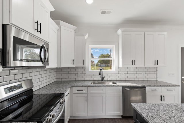 kitchen featuring light stone counters, white cabinets, sink, backsplash, and appliances with stainless steel finishes