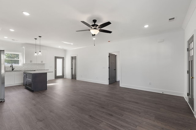 unfurnished living room featuring ceiling fan, sink, dark wood-type flooring, and crown molding