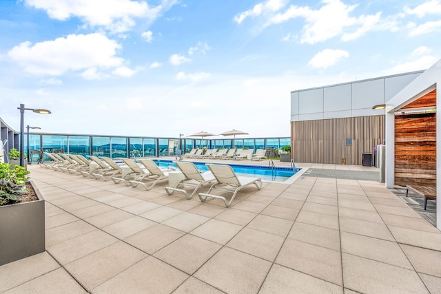 view of pool featuring a water view and a patio area