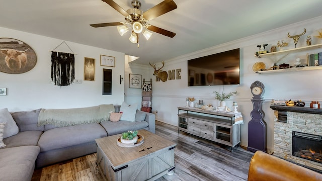 living room featuring ceiling fan, a fireplace, hardwood / wood-style floors, and crown molding