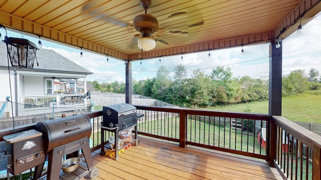 deck featuring ceiling fan, area for grilling, and a lawn