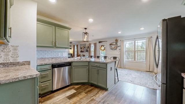 kitchen featuring light hardwood / wood-style floors, stainless steel appliances, green cabinets, and kitchen peninsula