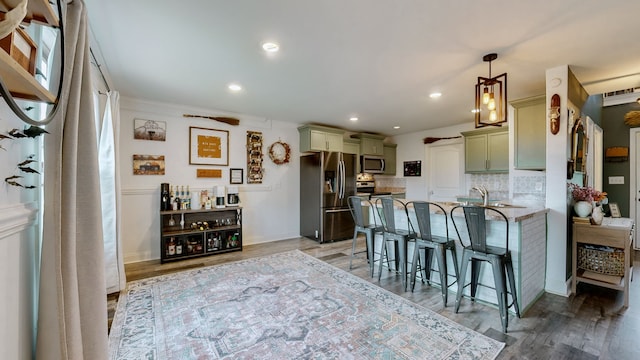 kitchen with appliances with stainless steel finishes, light stone counters, backsplash, pendant lighting, and wood-type flooring