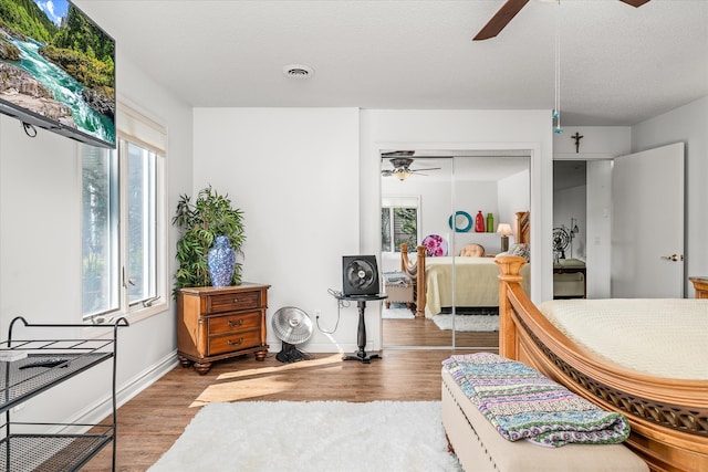 bedroom with a closet, hardwood / wood-style flooring, ceiling fan, and a textured ceiling