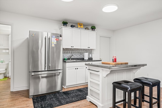 kitchen with stainless steel fridge, light hardwood / wood-style floors, white cabinetry, and a center island