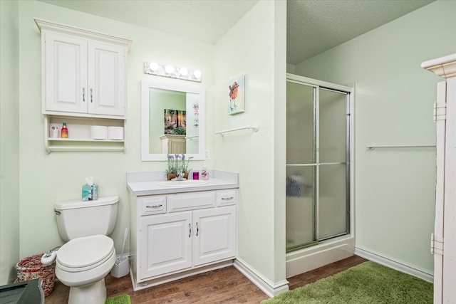 bathroom featuring vanity, hardwood / wood-style flooring, a shower with shower door, and toilet