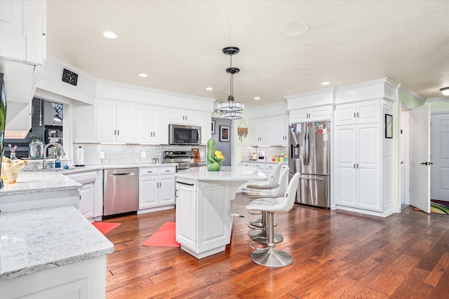 kitchen with pendant lighting, stainless steel appliances, dark hardwood / wood-style floors, and a center island