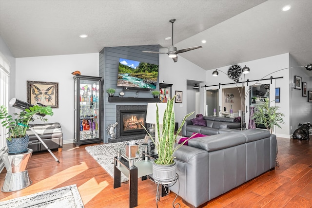 living room featuring high vaulted ceiling, a fireplace, a textured ceiling, ceiling fan, and hardwood / wood-style flooring