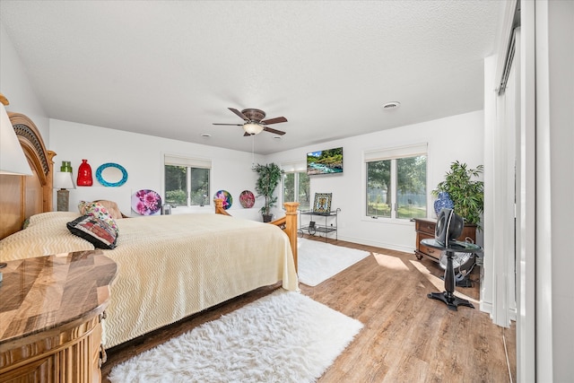 bedroom with multiple windows, a textured ceiling, hardwood / wood-style floors, and ceiling fan