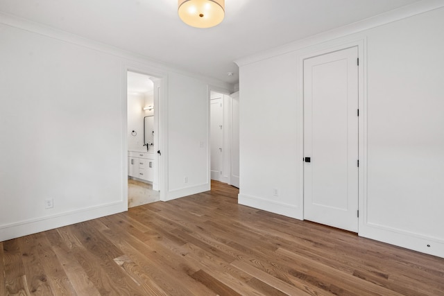 unfurnished bedroom featuring connected bathroom, hardwood / wood-style flooring, and crown molding