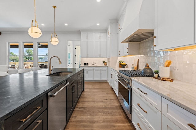 kitchen with custom range hood, white cabinetry, sink, and stainless steel appliances