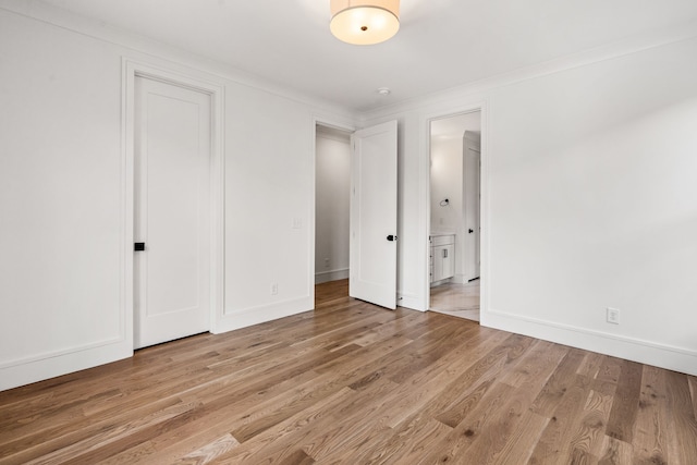 unfurnished bedroom with ensuite bath and light hardwood / wood-style flooring