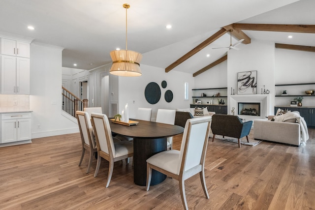 dining area featuring ceiling fan, vaulted ceiling with beams, and light hardwood / wood-style flooring