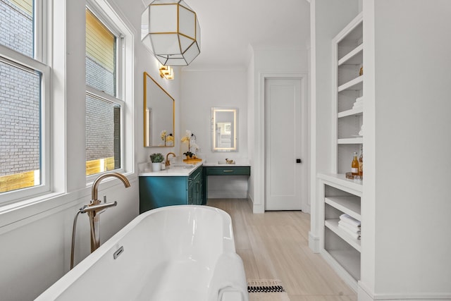 bathroom featuring ornamental molding, vanity, built in shelves, and a bathtub