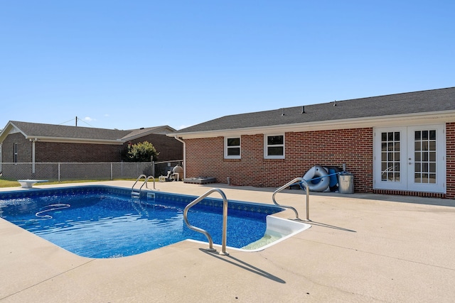 view of swimming pool with a patio, a diving board, and french doors