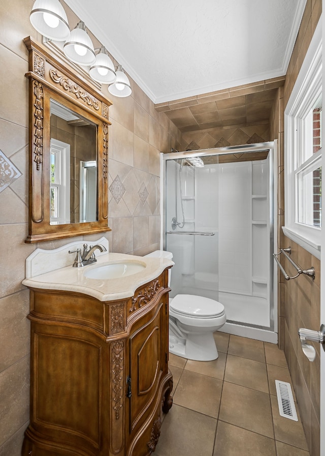 bathroom with tile walls, a shower with shower door, vanity, crown molding, and toilet