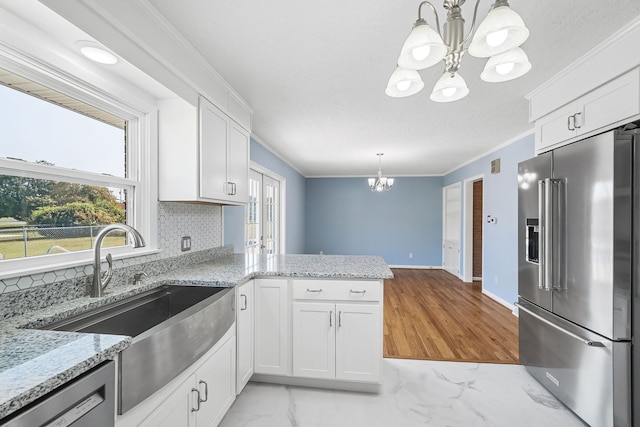 kitchen with a notable chandelier, white cabinets, kitchen peninsula, stainless steel appliances, and decorative light fixtures