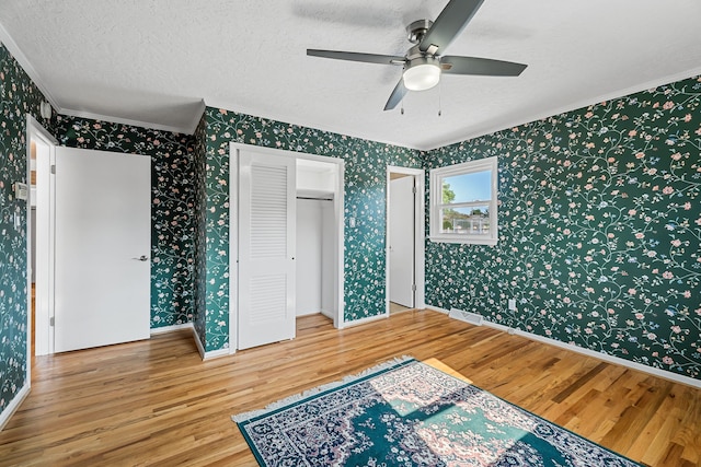 bedroom with a textured ceiling, ornamental molding, ceiling fan, and hardwood / wood-style flooring