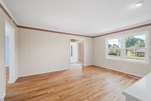 interior space featuring a textured ceiling, light hardwood / wood-style flooring, and ornamental molding