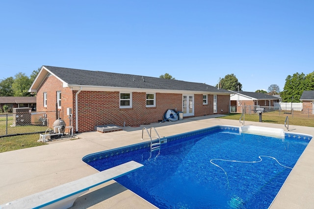 view of pool featuring a diving board, a lawn, and a patio