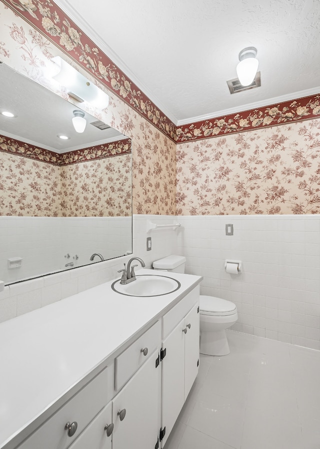 bathroom featuring tile patterned flooring, a textured ceiling, ornamental molding, vanity, and toilet