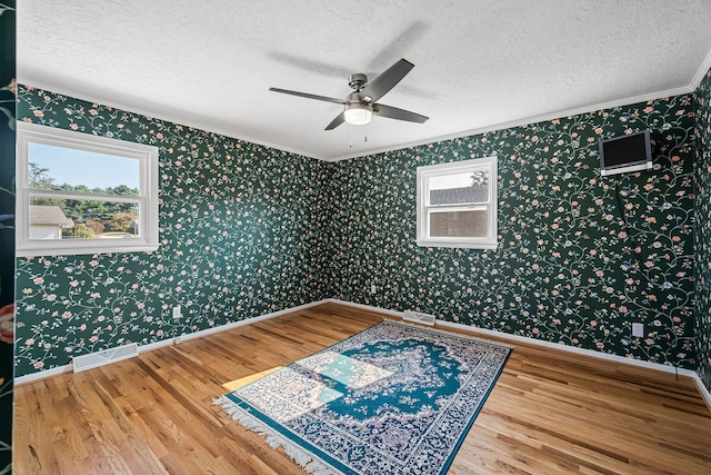 spare room with ceiling fan, ornamental molding, a textured ceiling, and hardwood / wood-style floors