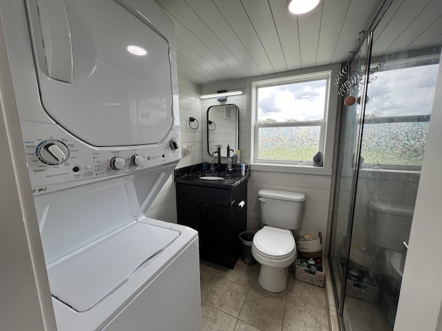 laundry room with light tile patterned flooring, stacked washer and dryer, and sink