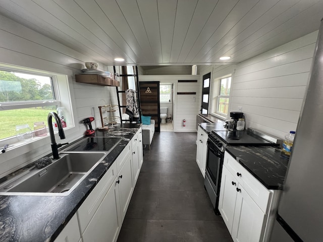 kitchen featuring white cabinets, wood walls, sink, stainless steel electric range, and wooden ceiling