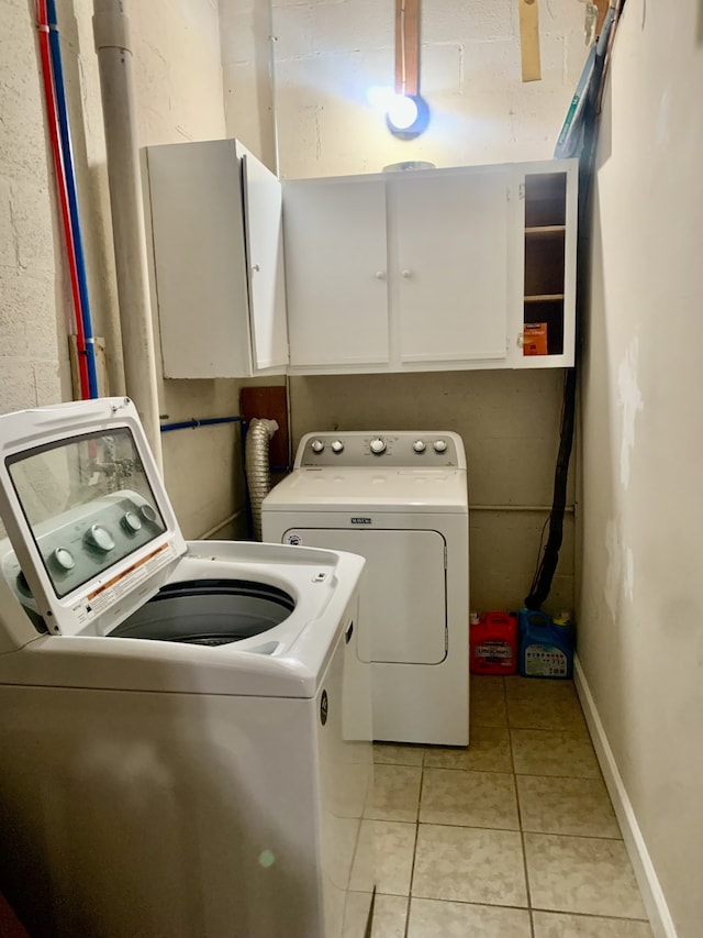 laundry room with cabinets, light tile patterned floors, and washing machine and dryer