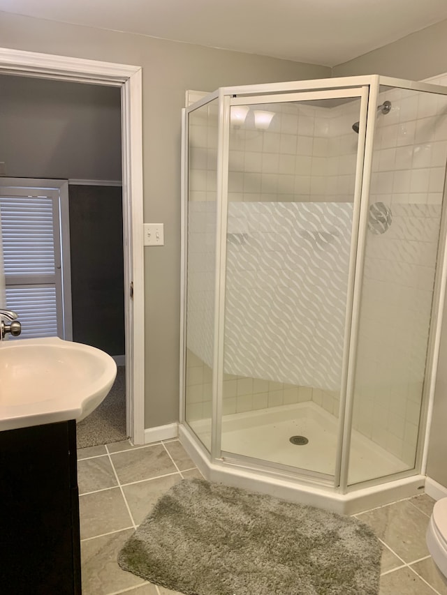 bathroom with tile patterned floors, a shower with door, vanity, and toilet