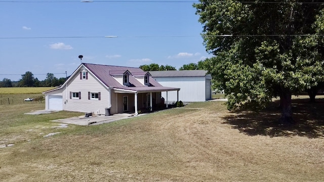 rear view of property with a patio, a yard, an outbuilding, and a garage