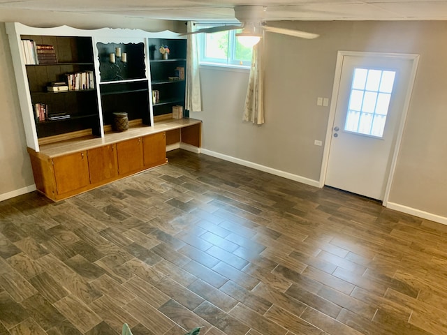 unfurnished living room featuring ceiling fan and dark wood-type flooring