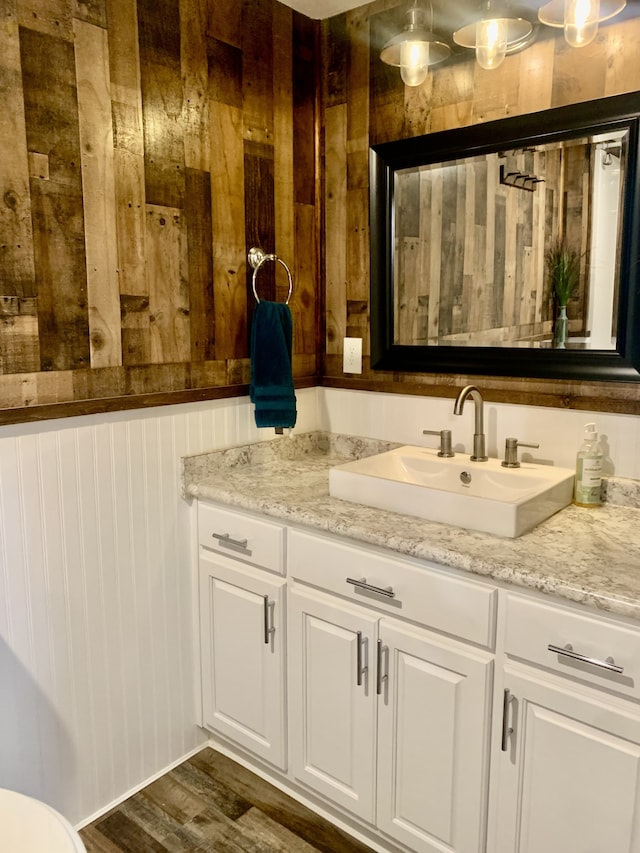 bathroom featuring wood walls, vanity, and hardwood / wood-style floors