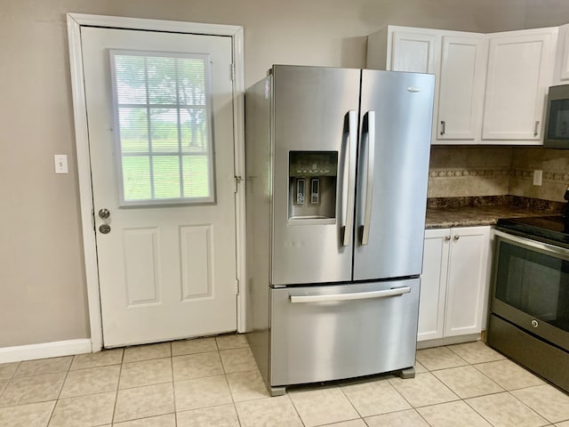 kitchen with appliances with stainless steel finishes, dark stone countertops, tasteful backsplash, white cabinets, and light tile patterned floors