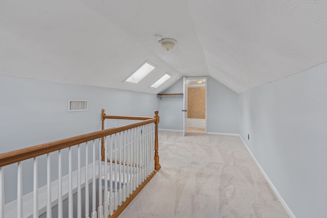 additional living space featuring vaulted ceiling with skylight and light colored carpet