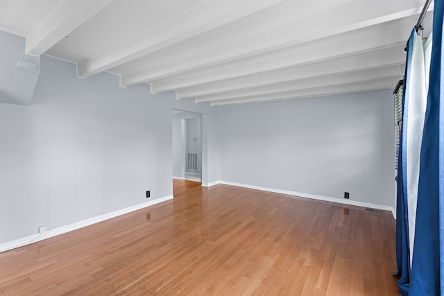 spare room featuring wood-type flooring, a barn door, and beam ceiling