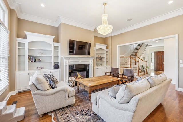 living room with hardwood / wood-style flooring, a chandelier, ornamental molding, and a healthy amount of sunlight