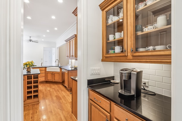 kitchen featuring light wood-type flooring, dishwasher, sink, backsplash, and crown molding