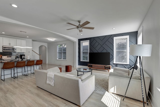 living room with light hardwood / wood-style flooring, ceiling fan, and sink