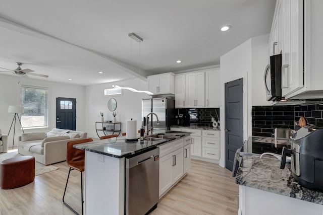 kitchen featuring an island with sink, stainless steel appliances, white cabinets, and sink