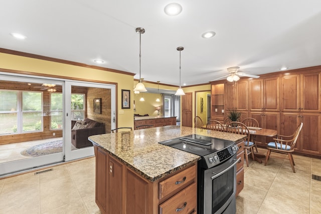 kitchen with pendant lighting, stainless steel range with electric cooktop, an island with sink, light stone countertops, and ceiling fan