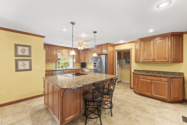 kitchen with ceiling fan, pendant lighting, a kitchen island, stainless steel appliances, and dark stone countertops